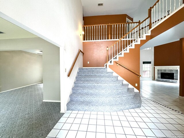 10511 Pemspice, San Antonio, TX 78240 - stairs featuring a high ceiling, carpet, a fireplace with raised hearth, tile patterned floors, and baseboards