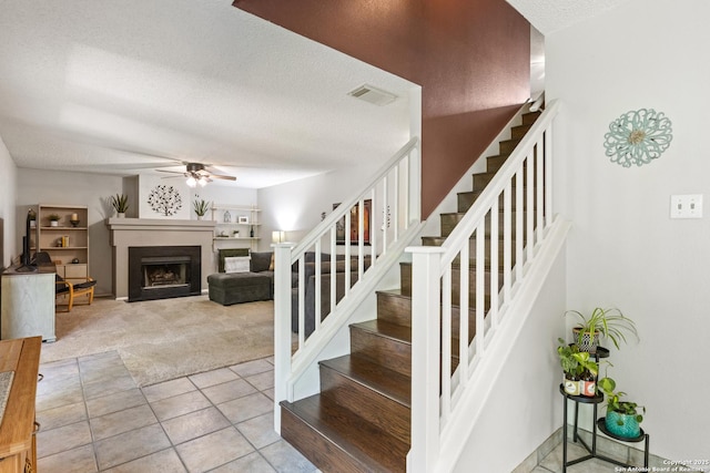 7705 Wood Blf, San Antonio, TX 78240 - staircase with carpet flooring, ceiling fan, a textured ceiling, tile patterned flooring, and a fireplace