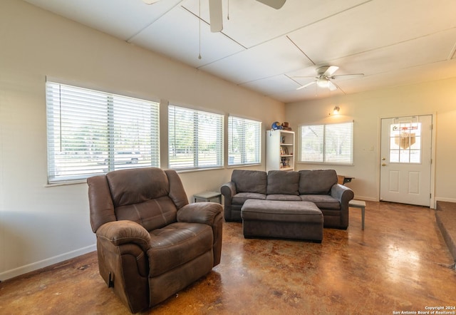 living area featuring a ceiling fan, baseboards, finished concrete floors, and plenty of natural light
