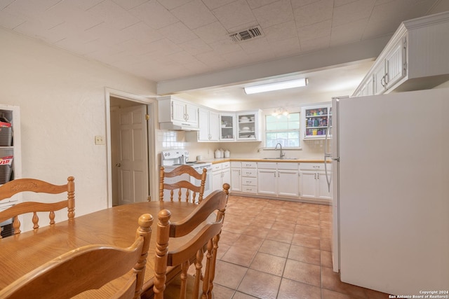 kitchen featuring white appliances, a sink, white cabinets, and glass insert cabinets