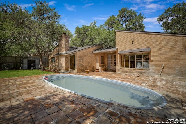 rear view of property featuring french doors, a patio, brick siding, and fence