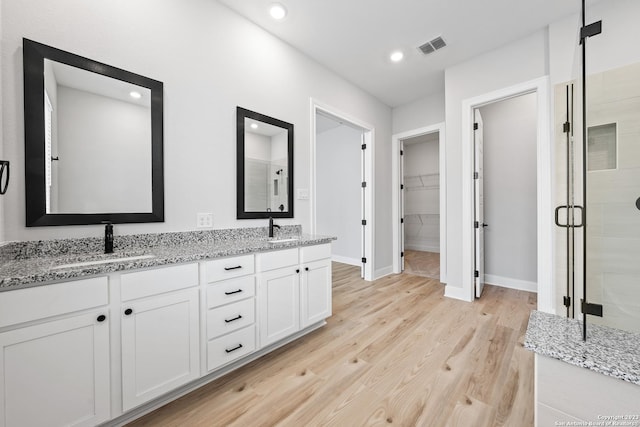 305 Lawrence Dr, Castroville, TX 78009 - full bath featuring a stall shower, wood finished floors, a walk in closet, baseboards, and double vanity