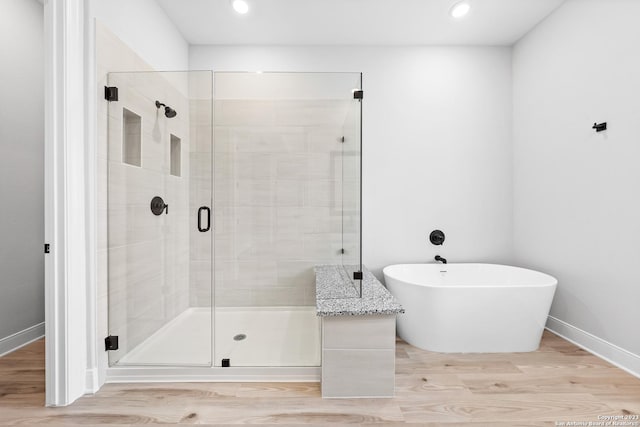 305 Lawrence Dr, Castroville, TX 78009 - bathroom featuring wood finished floors, a stall shower, a soaking tub, baseboards, and recessed lighting