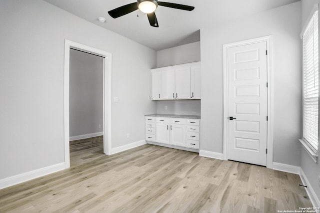 305 Lawrence Dr, Castroville, TX 78009 - unfurnished bedroom with light wood finished floors, baseboards, multiple windows, and ceiling fan