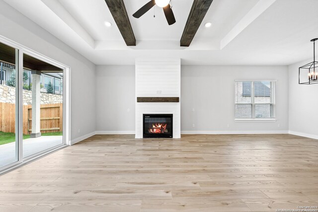 305 Lawrence Dr, Castroville, TX 78009 - unfurnished living room with light wood-style floors, beamed ceiling, a large fireplace, ceiling fan, and a chandelier