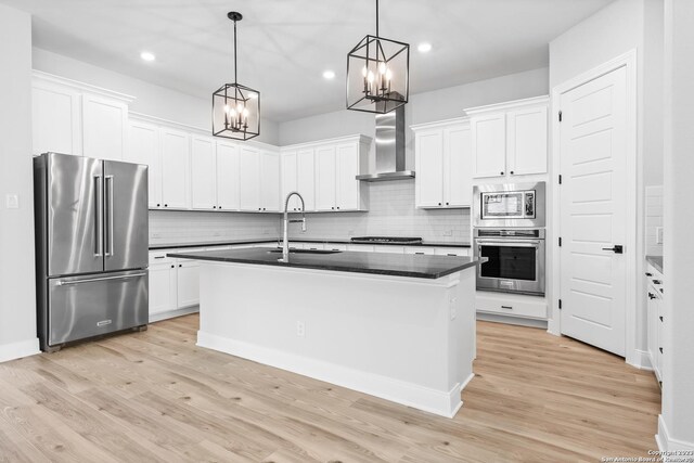 305 Lawrence Dr, Castroville, TX 78009 - kitchen featuring appliances with stainless steel finishes, a sink, wall chimney range hood, a chandelier, and dark countertops