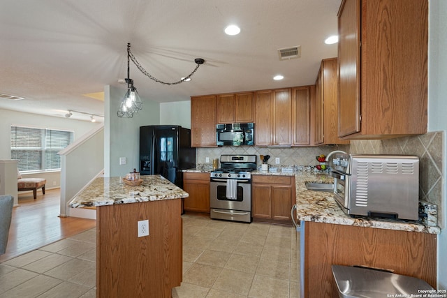 3738 Sumantra, San Antonio, TX 78261 - kitchen featuring black appliances, light tile patterned flooring, brown cabinetry, decorative backsplash, and a kitchen island