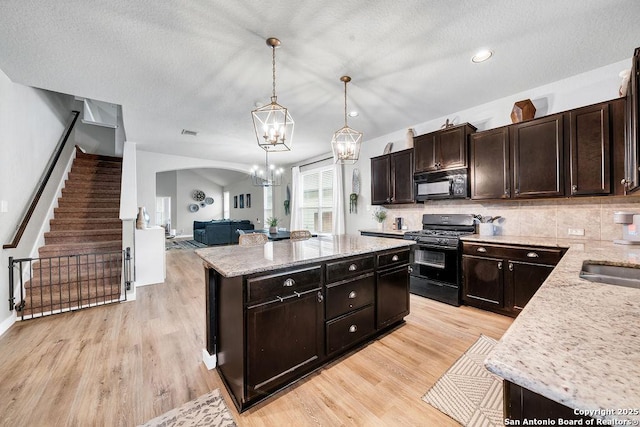 13410 Canyon Mdws, San Antonio, TX 78254 - kitchen with black appliances, a kitchen island, light wood-style floors, a chandelier, and light stone countertops