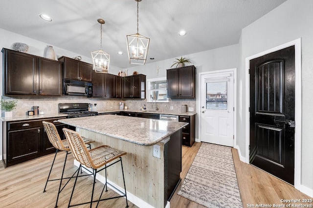 13410 Canyon Mdws, San Antonio, TX 78254 - kitchen with black appliances, a sink, a chandelier, a kitchen bar, and backsplash