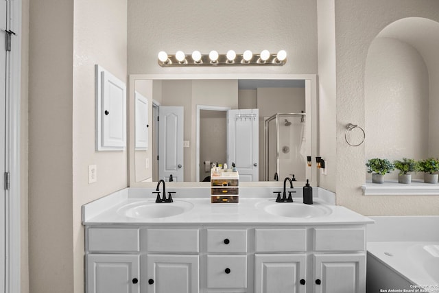 22841 San Saba Blf, San Antonio, TX 78258 - bathroom featuring a textured wall, a shower stall, a bath, and double vanity