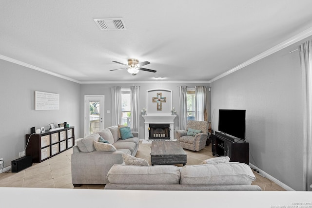22841 San Saba Blf, San Antonio, TX 78258 - tiled living area featuring a ceiling fan, baseboards, a glass covered fireplace, and ornamental molding