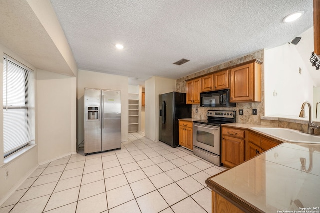 8255 Misty Willow, San Antonio, TX 78250 - kitchen featuring black appliances, a sink, a textured ceiling, decorative backsplash, and brown cabinetry