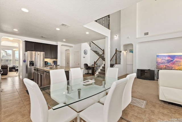 8515 Desert Cv, San Antonio, TX 78254 - dining space featuring arched walkways, stairway, recessed lighting, light tile patterned flooring, and a textured ceiling