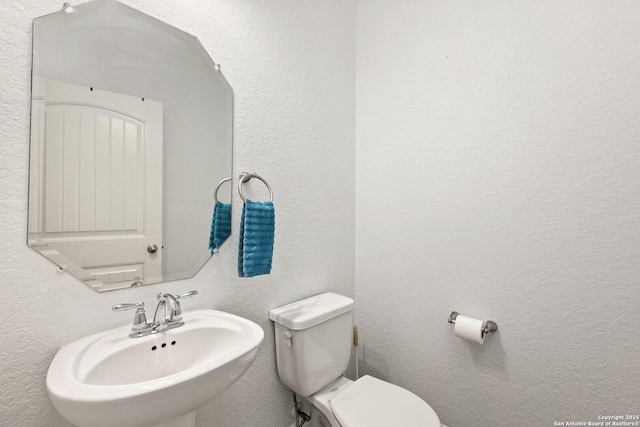 8515 Desert Cv, San Antonio, TX 78254 - half bathroom featuring a sink, toilet, and a textured wall
