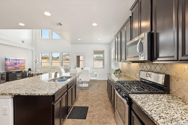 8515 Desert Cv, San Antonio, TX 78254 - kitchen with appliances with stainless steel finishes, a sink, open floor plan, tasteful backsplash, and light stone counters