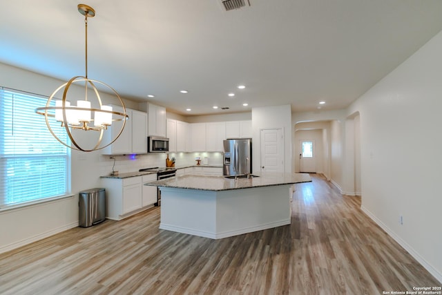 26323 Gibraltar, Boerne, TX 78015 - kitchen with appliances with stainless steel finishes, light wood-style floors, a chandelier, light stone counters, and tasteful backsplash