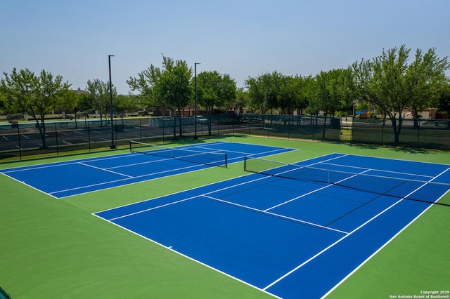 view of tennis court featuring community basketball court and fence