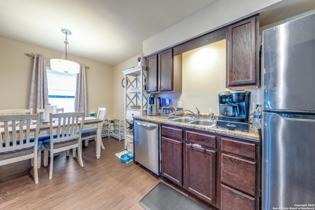 255 E Rampart Unit 401, San Antonio, TX 78216 - kitchen with appliances with stainless steel finishes, a sink, light wood finished floors, dark brown cabinetry, and decorative light fixtures