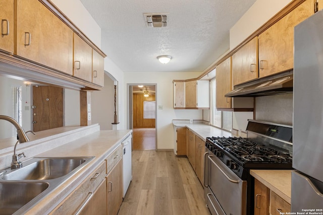 kitchen featuring stainless steel appliances, under cabinet range hood, a sink, light wood-type flooring, and light countertops