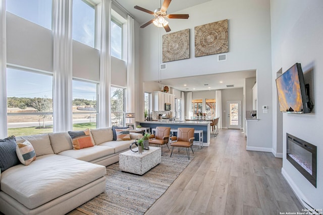 178 Jax Loop, San Antonio, TX 78253 - living room featuring a high ceiling, plenty of natural light, a ceiling fan, light wood-type flooring, and baseboards