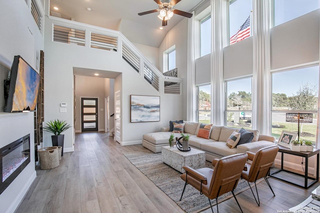 178 Jax Loop, San Antonio, TX 78253 - living area featuring a high ceiling, wood finished floors, ceiling fan, a glass covered fireplace, and baseboards