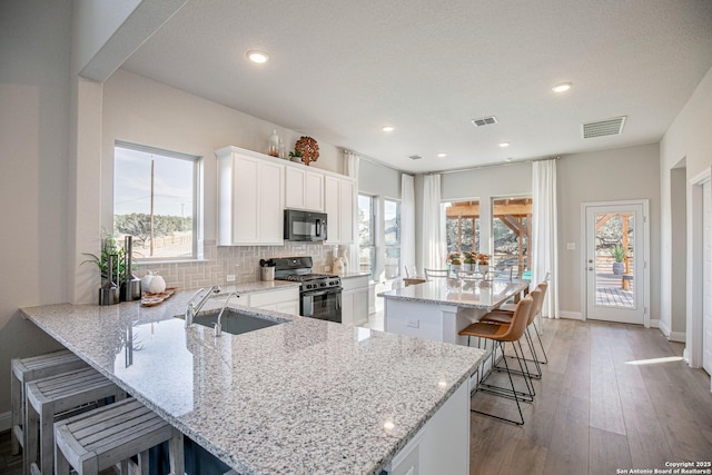 178 Jax Loop, San Antonio, TX 78253 - kitchen featuring black appliances, a sink, a kitchen bar, decorative backsplash, and white cabinets