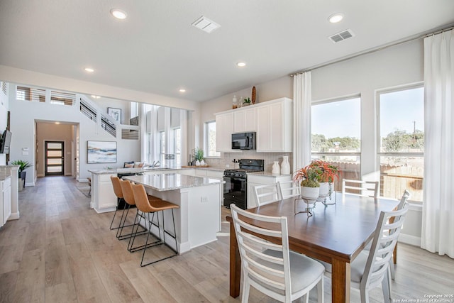 178 Jax Loop, San Antonio, TX 78253 - kitchen with black appliances, a kitchen island, white cabinetry, light stone countertops, and light wood-style floors