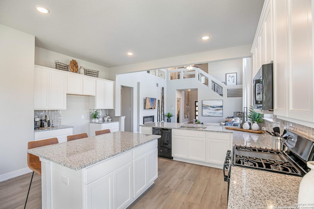 178 Jax Loop, San Antonio, TX 78253 - kitchen featuring black appliances, light wood-style flooring, a sink, backsplash, and a peninsula