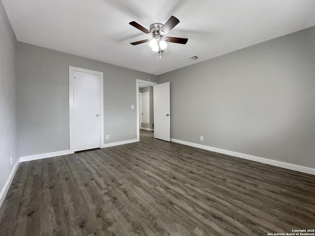 unfurnished bedroom featuring baseboards, dark wood-type flooring, and a ceiling fan