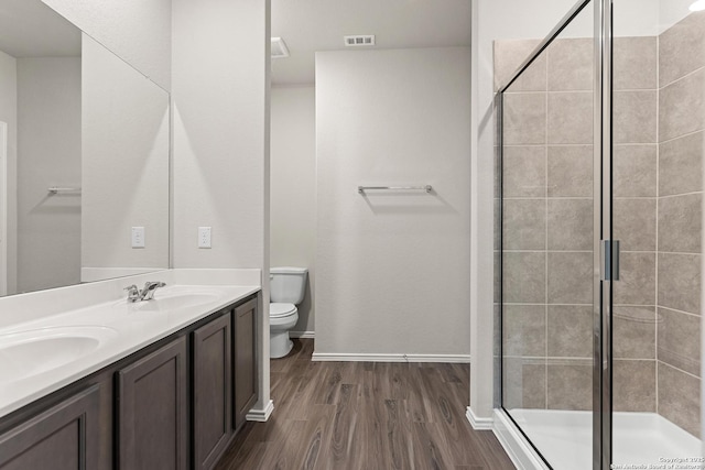9318 Graze Br, San Antonio, TX 78211 - full bathroom with wood finished floors, toilet, baseboards, a shower stall, and double vanity