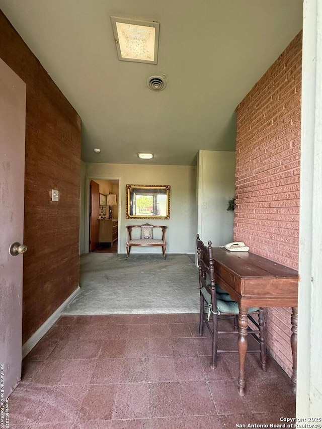 carpeted home office with brick wall