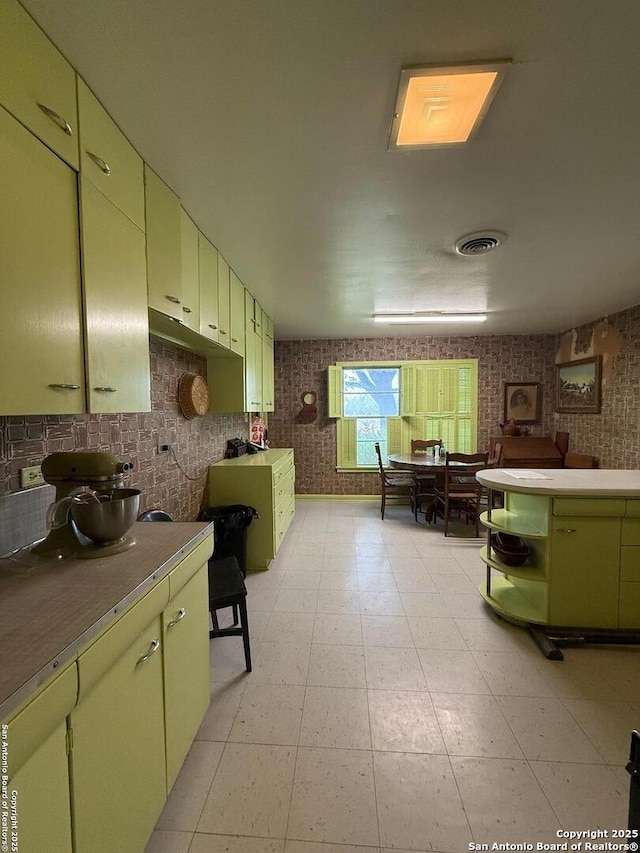 kitchen featuring green cabinetry, open shelves, light countertops, and light flooring