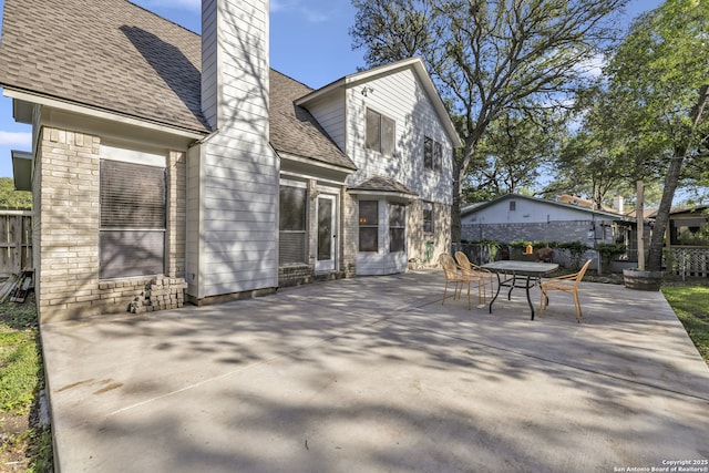 11819 Rousseau, San Antonio, TX 78251 - back of house featuring a chimney, a patio, roof with shingles, outdoor dining area, and fence