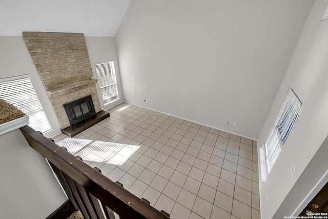11819 Rousseau, San Antonio, TX 78251 - unfurnished living room featuring high vaulted ceiling, light tile patterned floors, a fireplace, and baseboards
