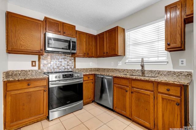 11819 Rousseau, San Antonio, TX 78251 - kitchen featuring stainless steel appliances, a sink, brown cabinetry, tasteful backsplash, and a textured ceiling