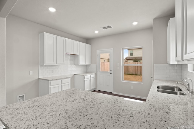 9410 Graze Land, San Antonio, TX 78211 - kitchen with light stone counters, a sink, backsplash, white cabinets, and recessed lighting