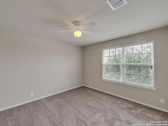 carpeted spare room featuring a ceiling fan and baseboards