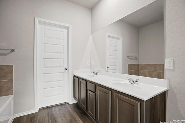 bathroom with wood finished floors, double vanity, and a tub