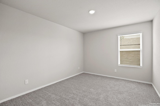 carpeted empty room featuring baseboards