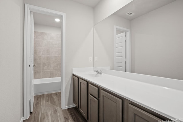 bathroom with vanity, wood finished floors, and shower / washtub combination