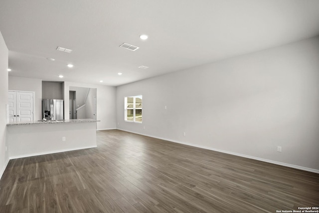 unfurnished living room featuring dark wood-type flooring, recessed lighting, and baseboards