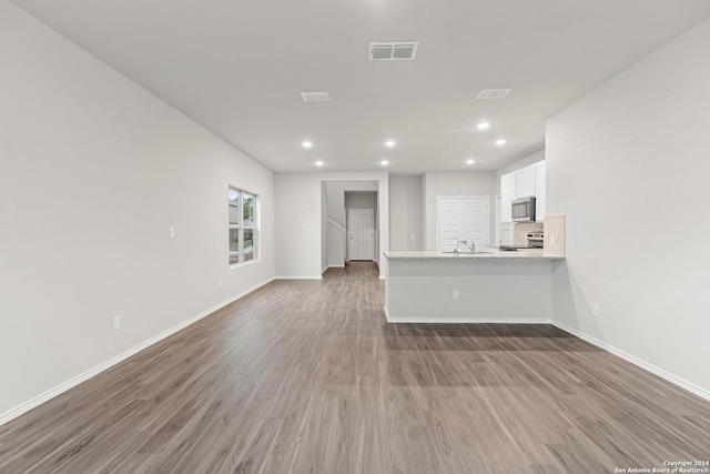 9322 Graze Br, San Antonio, TX 78211 - unfurnished living room featuring wood finished floors, recessed lighting, baseboards, and a sink