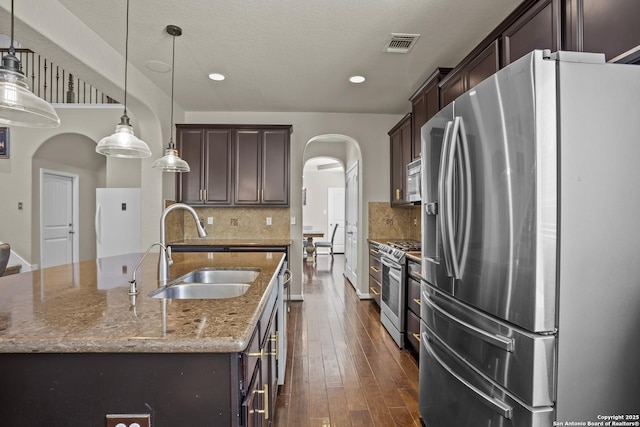 11734 Violet Cv, San Antonio, TX 78253 - kitchen featuring stainless steel appliances, a sink, arched walkways, dark brown cabinets, and recessed lighting