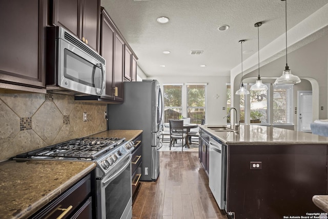 11734 Violet Cv, San Antonio, TX 78253 - kitchen with stainless steel appliances, a sink, dark brown cabinets, dark wood-style flooring, and an island with sink