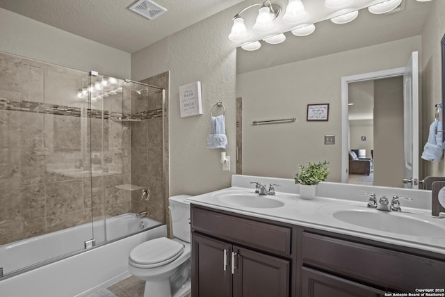 11734 Violet Cv, San Antonio, TX 78253 - bathroom with double vanity, toilet, bath / shower combo with glass door, a textured ceiling, and a textured wall