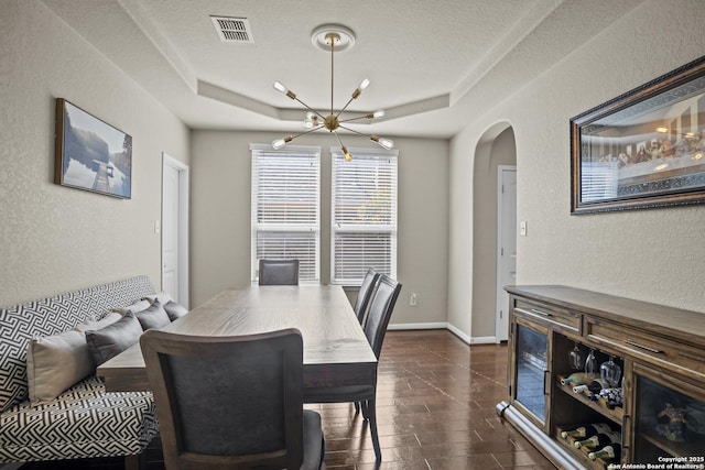 11734 Violet Cv, San Antonio, TX 78253 - dining space featuring a tray ceiling, a textured wall, arched walkways, and a chandelier