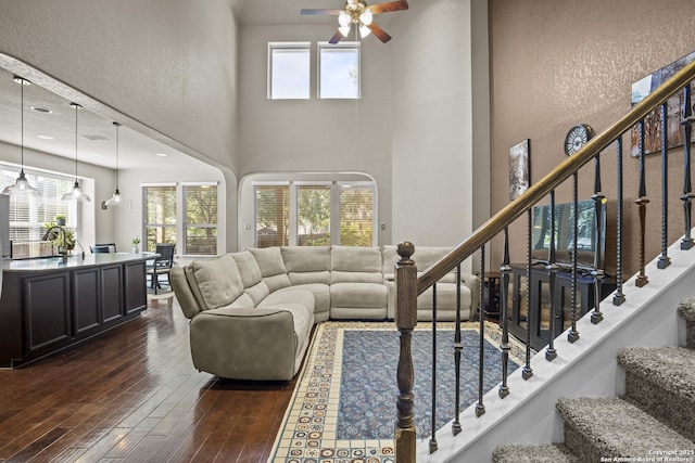 11734 Violet Cv, San Antonio, TX 78253 - living area with dark wood-style flooring, ceiling fan, stairs, a textured wall, and a towering ceiling