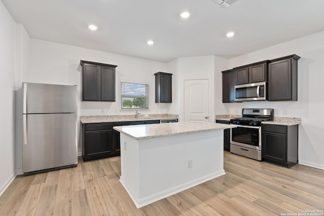 10827 Quinn Ct, San Antonio, TX 78252 - kitchen featuring appliances with stainless steel finishes, a kitchen island, light wood-style floors, light stone countertops, and recessed lighting