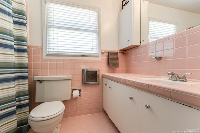 2027 Edgehill Dr, San Antonio, TX 78209 - full bath featuring tile walls, tile patterned floors, toilet, vanity, and a wainscoted wall