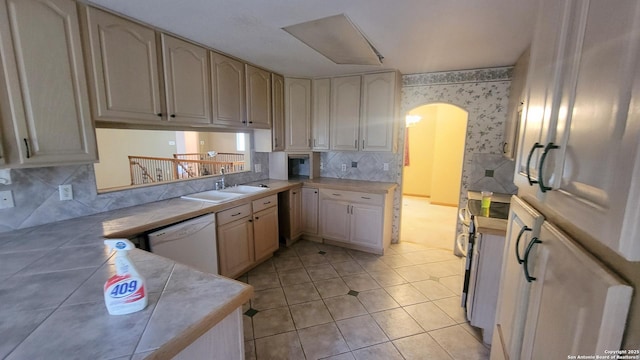 7 Glen Cove Dr, Seguin, TX 78155 - kitchen featuring white dishwasher, wallpapered walls, a sink, arched walkways, and backsplash